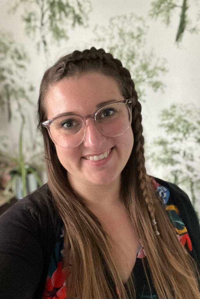 A headshot of Emilie, who wears glasses and a braid in her hair
